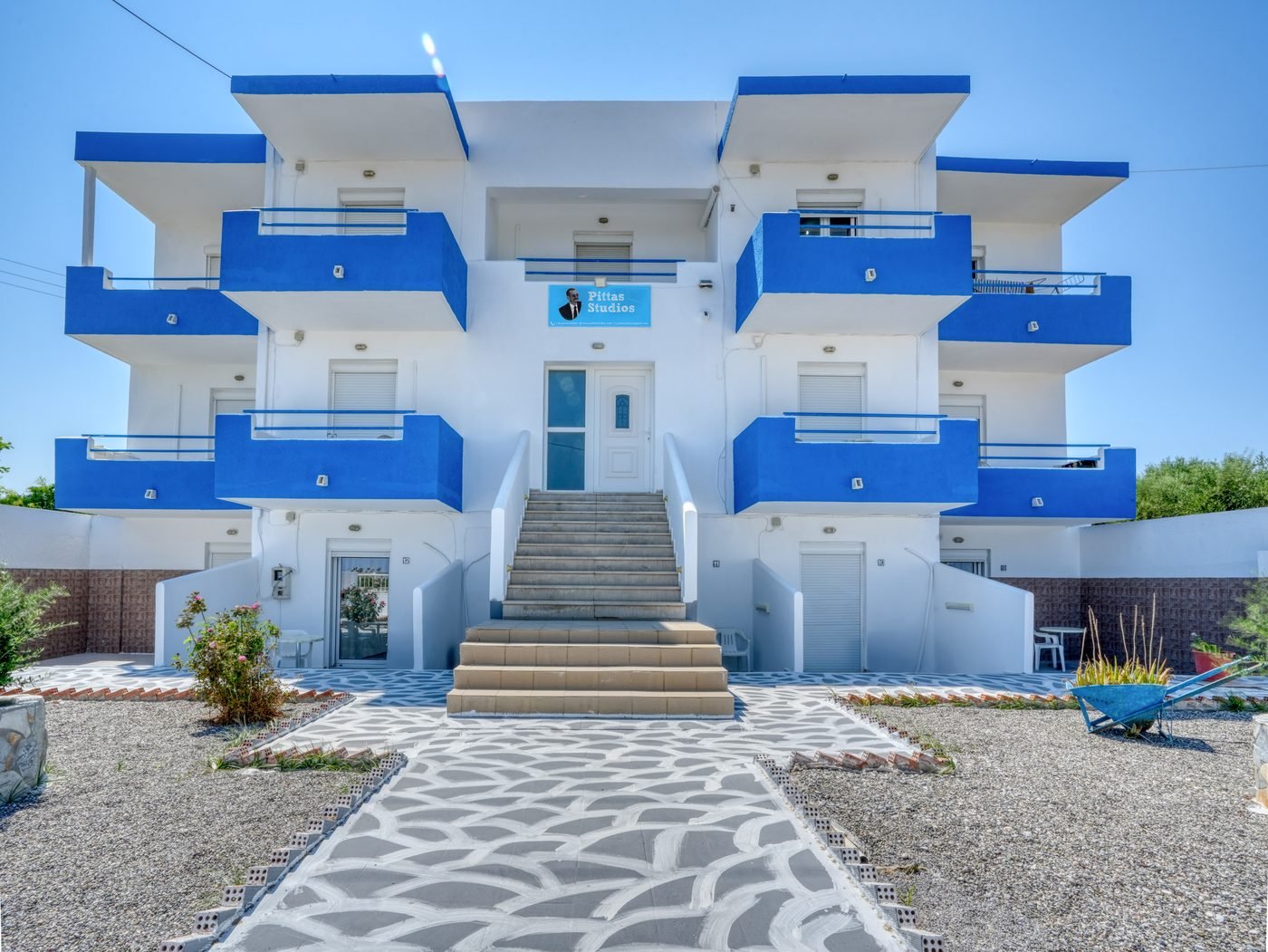 Pittas Studios front elevation — white building with blue balconies among the olive groves